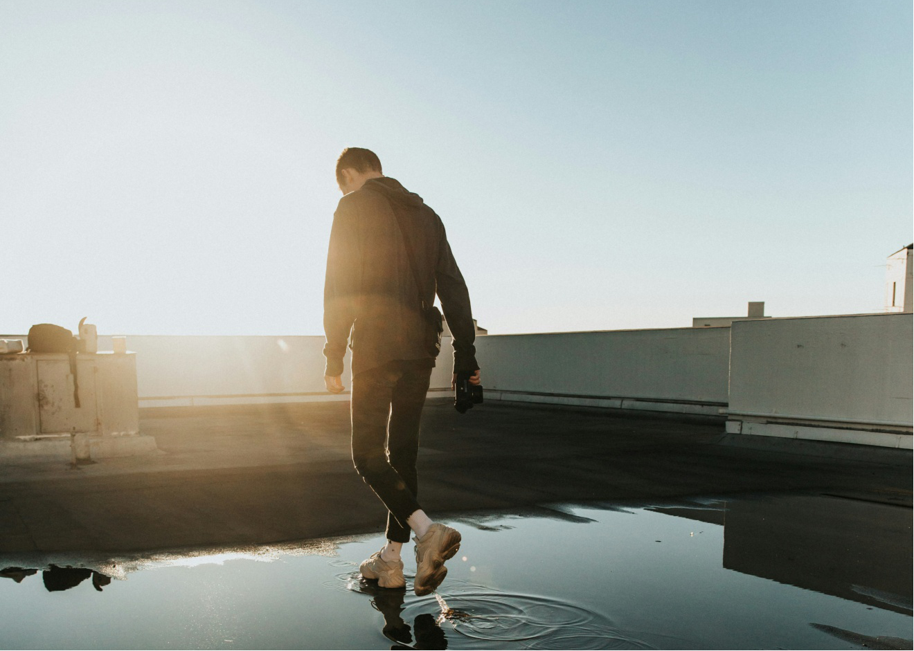A man walking on a roof with a water puddle beneath his feet
