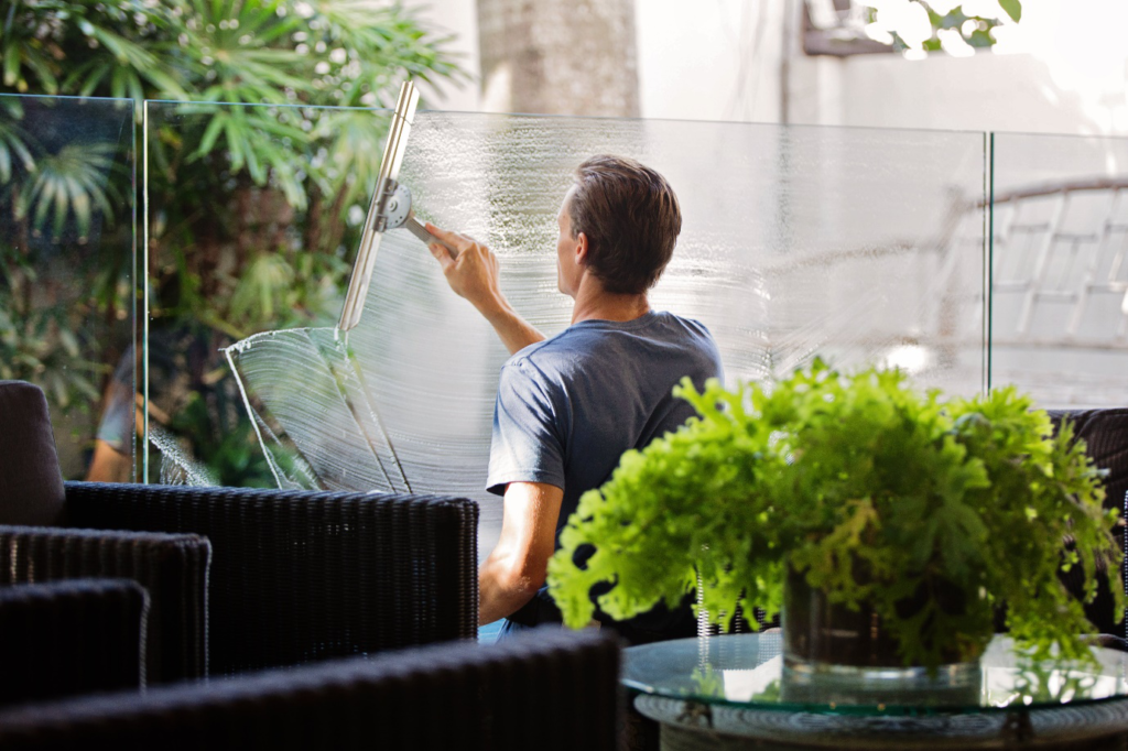 a man cleaning a glass wall near a sofa