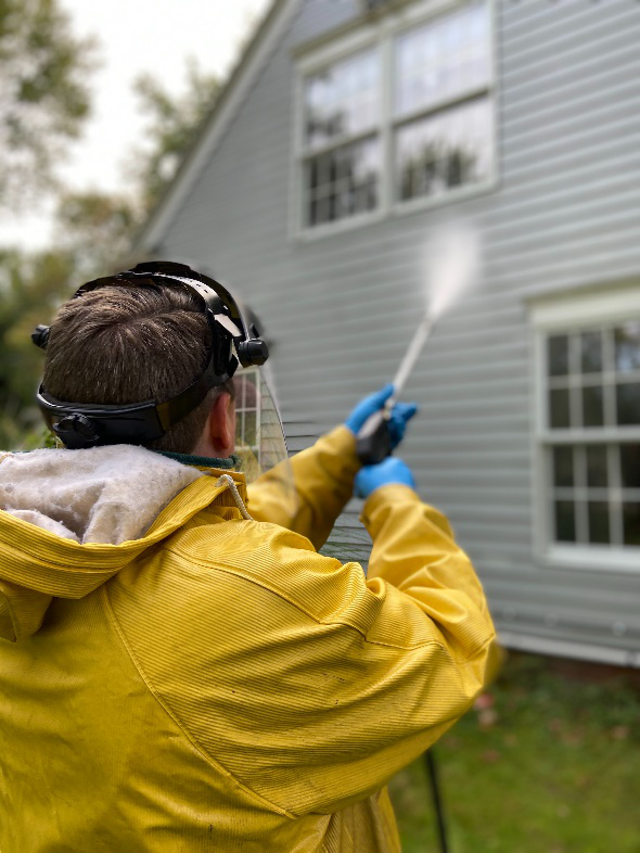 A professional pressure-washing a house